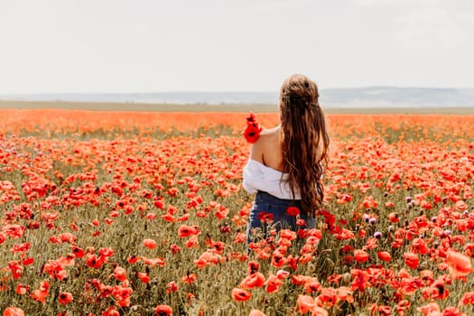 Woman poppies field. Back view of a happy woman with long hair in a poppy field and enjoying the beauty of nature in a warm summer day