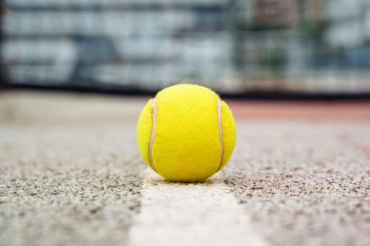 Closeup view of yellow tennis ball lying on acrylic tennis hard court surface with empty blank copy space.