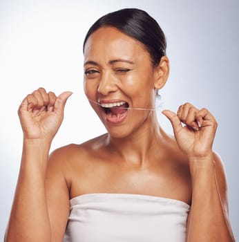 Dental, portrait or mature woman flossing teeth for beauty or wellness in studio on white background. Smile, self care or healthy senior model grooming or cleaning her tooth or mouth for hygiene.