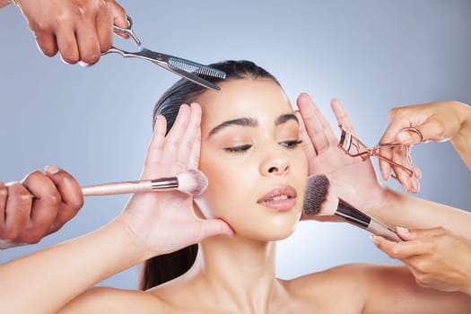 Salon, makeup and face of woman with brush in studio for wellness, beauty and cosmetics on blue background. Cosmetology, hands and girl with brushes for cosmetic application, foundation and products.