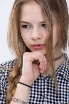 Bust of a thoughtful girl. Close-up of a woman's face. Girl with a thoughtful face. Posing on a white background. Photo session in a studio. Person wearing checkered shirt.