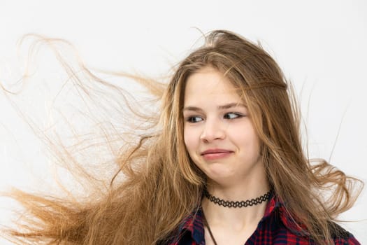 Close-up on the face of a young girl making a puzzled face. Making funny faces. The girl's hair is in disarray. The wind has tangled the woman's long hair. The hairstyle is blown by the wind.