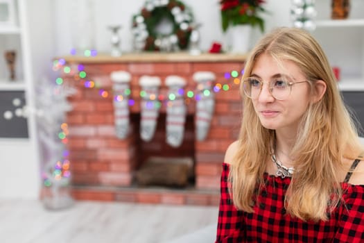Close-up on bust of young girl against background of brick fireplace. The girl has blonde loose hair. The brick fireplace can be seen in the background. Blurred second plan.
