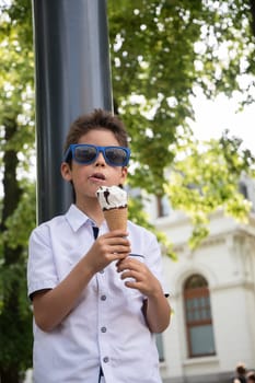 Cute child boy with a dirty face eats ice cream, the child enjoys dessert on a walk in the park, High quality photo