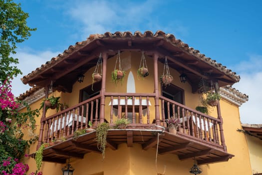 Image of street cafe on the wooden balcony with chairs and tables, covered with red flowers