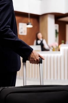 Hotel guest entering reception with luggage, travelling abroad to attend important business meetings. Entrepreneur approaching front desk for check in, booking accommodation. Close up.