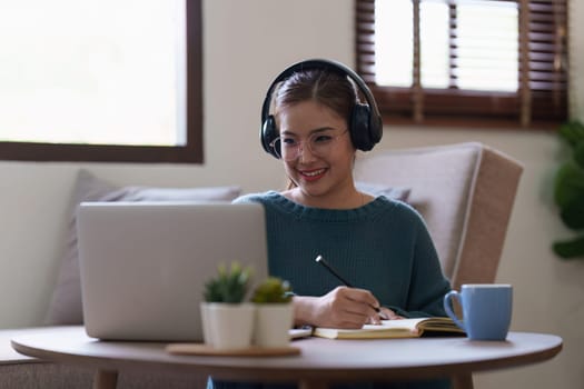 Young asian relaxed smiling pretty woman relaxing with laptop at home. Female feeling joy enjoying with mobile phone on cozy couch.