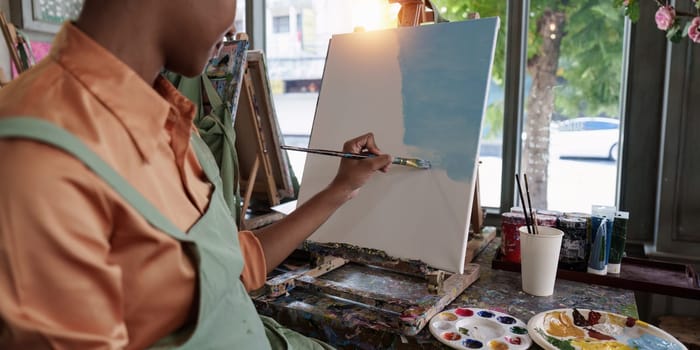 Beautiful american african artist woman painting in art studio at the university classroom.