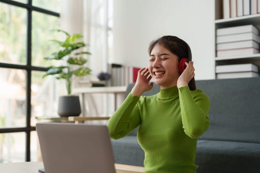 Young asian relaxed smiling pretty woman relaxing with laptop at home. Female feeling joy enjoying with mobile phone on cozy couch.