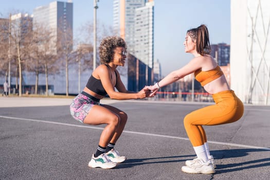 two multiethnic female friends exercising together in an urban park, concept of friendship and sportive lifestyle