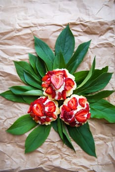 Beautiful and bright cupcakes with strawberries lie on green leaves, close-up.