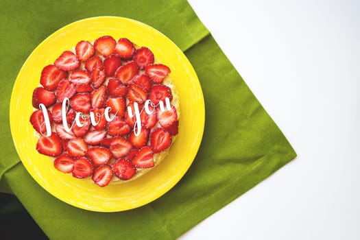 A beautiful strawberry cake is on the table, the inscription I love you.