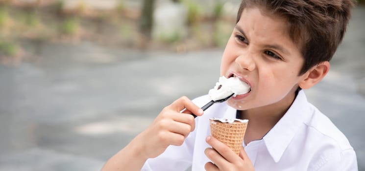 Cute child boy with a dirty face eats ice cream, the child enjoys dessert on a walk in the park, High quality photo