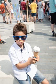 Cute child boy with a dirty face eats ice cream, the child enjoys dessert on a walk in the park, High quality photo