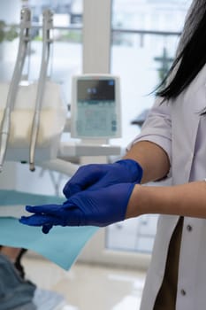 Dentist putting on gloves before starting working on patient's mouth, Woman doctor. Woman dentist. Dentist clinic. Dentist's office. Dental clinic