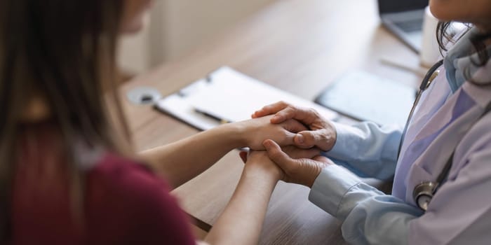 Happy woman visiting doctor senior , getting optimistic news after medical checkup, therapy. Therapist holding hand of patient, giving hope, support, congratulating on goor treatment result.