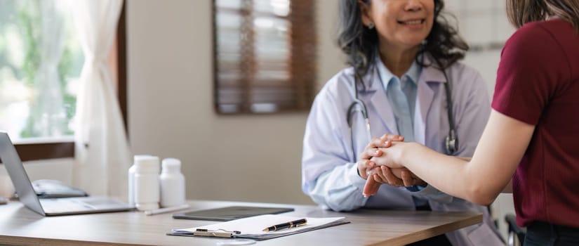 Happy woman visiting doctor senior , getting optimistic news after medical checkup, therapy. Therapist holding hand of patient, giving hope, support, congratulating on goor treatment result.