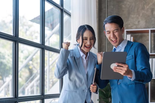 Two asian businesspleplo celebrate with laptop, success happy pose, E-commerce, get good news on laptop. internet technology, or startup small business concept.