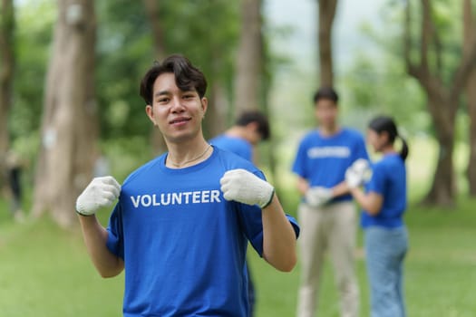 Young Asian Volunteers with garbage bags cleaning park area. Ecology, Charitable organization concept.