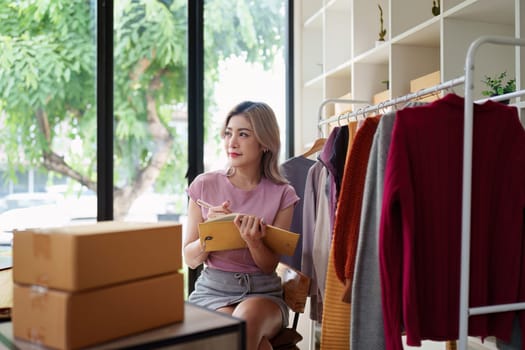 Asian female fashion designer sketches the design of a new dress in a fashion studio.