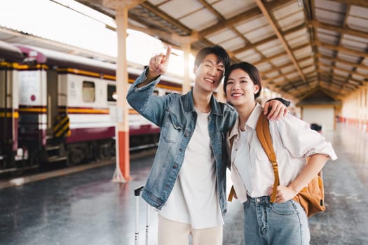 Asian couple at railway station have happy moment. Tourism and travel in the summer.