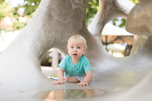 Child playing on outdoor playground. Toddler plays on school or kindergarten yard. Active kid on stone sculpured slide. Healthy summer activity for children. Little boy climbing outdoors