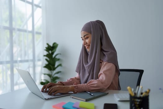 Muslim woman manager, lawyer or company employee holding accounting bookkeeping documents checking financial data or marketing report working in office with laptop. Paperwork management.