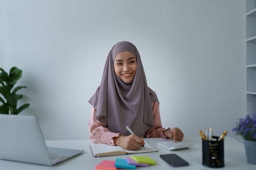 financial, Planning, Marketing and Accounting, portrait of Muslim woman employee checking financial statements using documents and calculators at work.