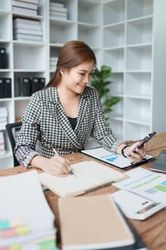 Consultant, advisor, Asian business woman working on the computer and using smartphone mobile talking work financial and marketing business planning company profits, marketing planning budget
