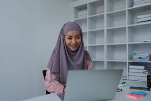 Muslim woman manager, lawyer or company employee holding accounting bookkeeping documents checking financial data or marketing report working in office with laptop. Paperwork management.