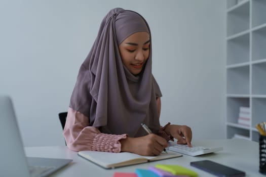 financial, Planning, Marketing and Accounting, portrait of Muslim woman employee checking financial statements using documents and calculators at work.