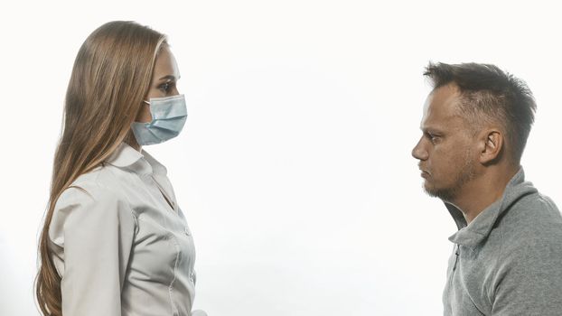 Medic looking at male patient who came for tests wearing a medical face mask. Sad man looking at her with sad eyes. Isolated on white background. Tinted image.