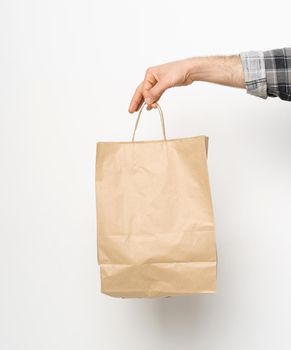 Man hand in plaid shirt twisted sleeve hand holding brown paper bag isolated on white background. Delivery concept. Paper bag for takeaway food. Delivery carrying.