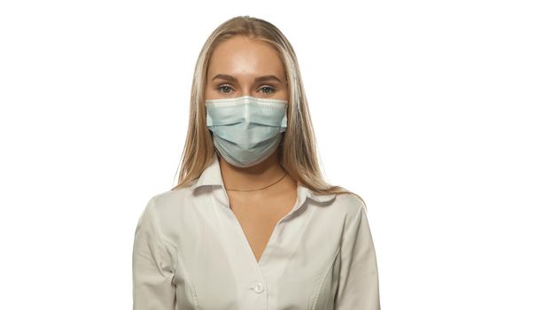 Charing blond haired nurse in a medical mask and white uniform looking at the camera. Isolated on white background.