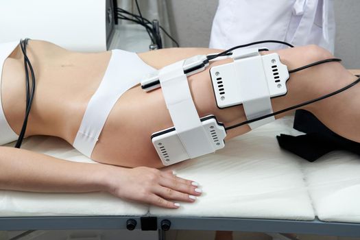 Beautiful woman getting electro stimulation therapy. Laser lipo equipment. Cosmetic fat reduce treatment. Woman in medicine salon. Anti cellulite procedure.