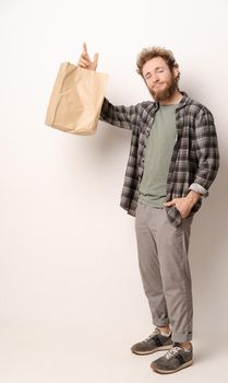Man in plaid shirt holding brown paper bag isolated on white background. Delivery concept. Paper bag for takeaway food. Courier with a bag on white background.