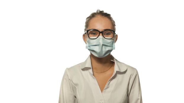 Positive looking young blond nurse in eye glasses looking at the camera wearing white medical uniform isolated on white background.