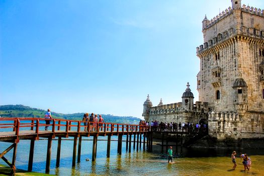 Lisbon, Portugal- 19 May, 2018: Tourists visiting Belem Tower in a low tide day in Lisbon in a sunny day of Spring.