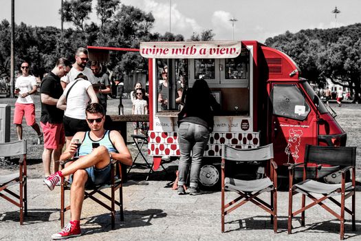 Lisbon, Portugal- 20 May, 2018: Tourists drinking wine at a street stall in Lisbon in a sunny day of May