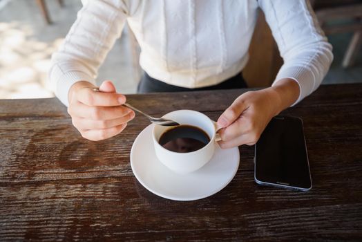 Close up of hands woman coffee and moblie on wood table