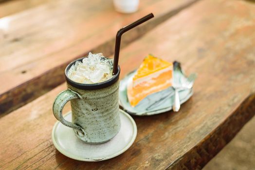 orange cake with ice coffee on wood table