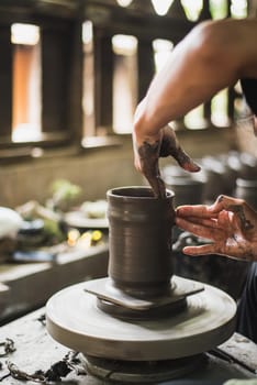 Closeup potter's hands shaping soft clay to make an earthen pot