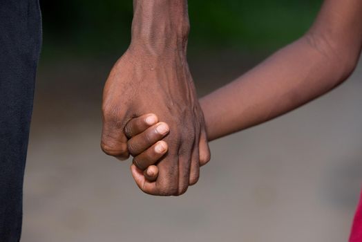 father and little son holding hands walking on a road. the father's hand lead his son into the wild with confidence in the outdoors protecting him.the parental concept of parental care. road to life.