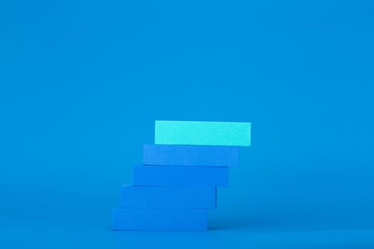 Business or personal development trendy modern concept. Ladder of success. Blue blocks as ladder on blue background with copy space