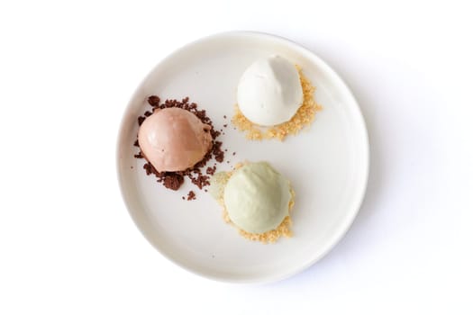 Colorful balls of ice cream on a white plate isolated