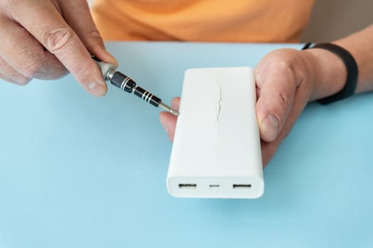 Power bank in hand, a battery that has become unusable, expands and swells until the case breaks. Equipment repair. There is a risk of explosion