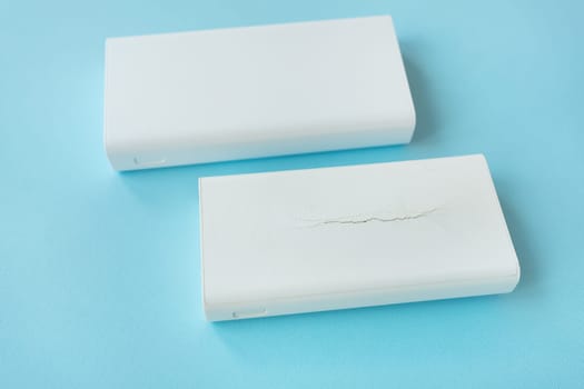Two power bank new and old with a crack on the case. An old battery that has become unusable expands and swells until the case breaks