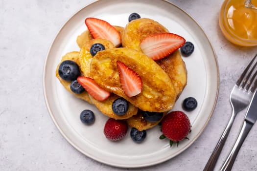 Torrijas, Spanish Style French Toast Served With Orange Topping, Glaze, Fresh Blueberries, Strawberry On Green Plate, Wooden Table. A Half Of Orange. Spanish Dessert. Horizontal plane.