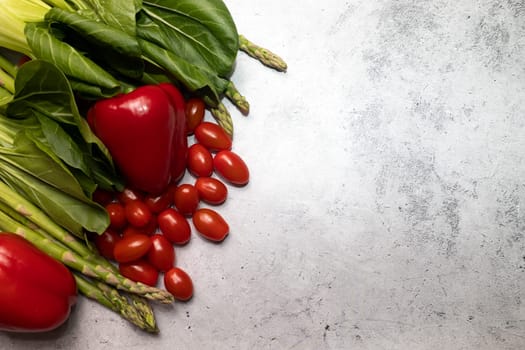 Mockup Assortment Of Fresh Organic Home Grown Red Green Vegetables On Gray Granite Table. Asparagus Plant, Bell Pepper, Bok Choy, Red Leaf Lettuce, Cherry Tomatoes. Flat lay. Horizontal, copy space