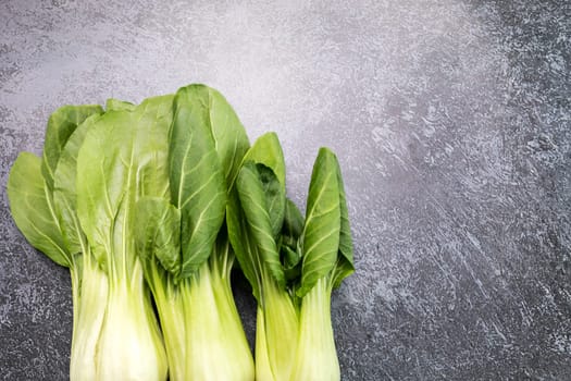 Fresh Organic Pak Choi, Bok Choy, a Chinese Cabbage, Raw Natural Healthy Vegetable Lying On Gray Granite Table, Flat Lay, Top View. Asian Cuisine. Horizontal Plane, Copy Space For Text.